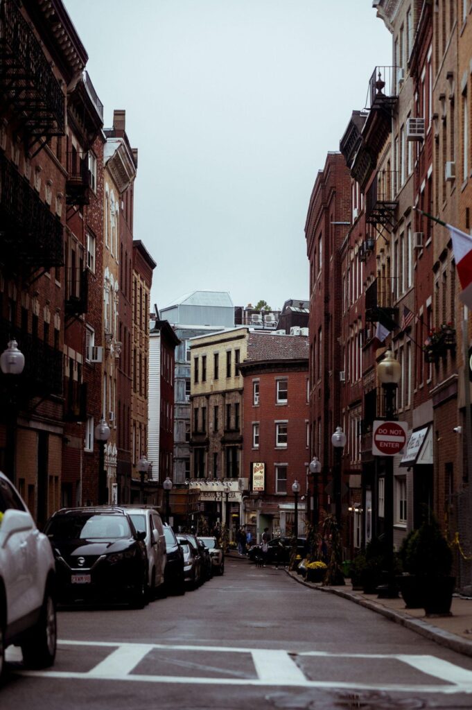 A row of historic red-brick row houses on a narrow street in Boston’s North End